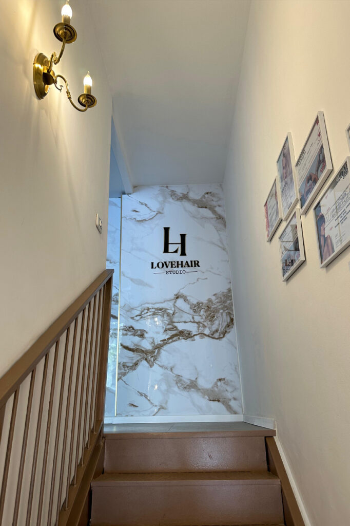 גרם מדרגות בכניסה ל־LOVEHAIR Studio עם לוגו על קיר שיש